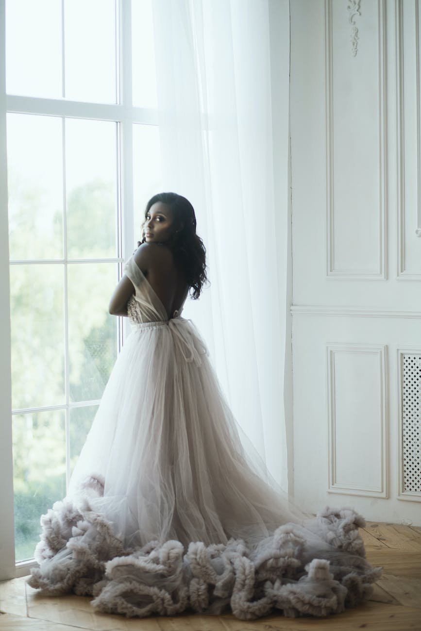 woman in white wedding dress standing near the window